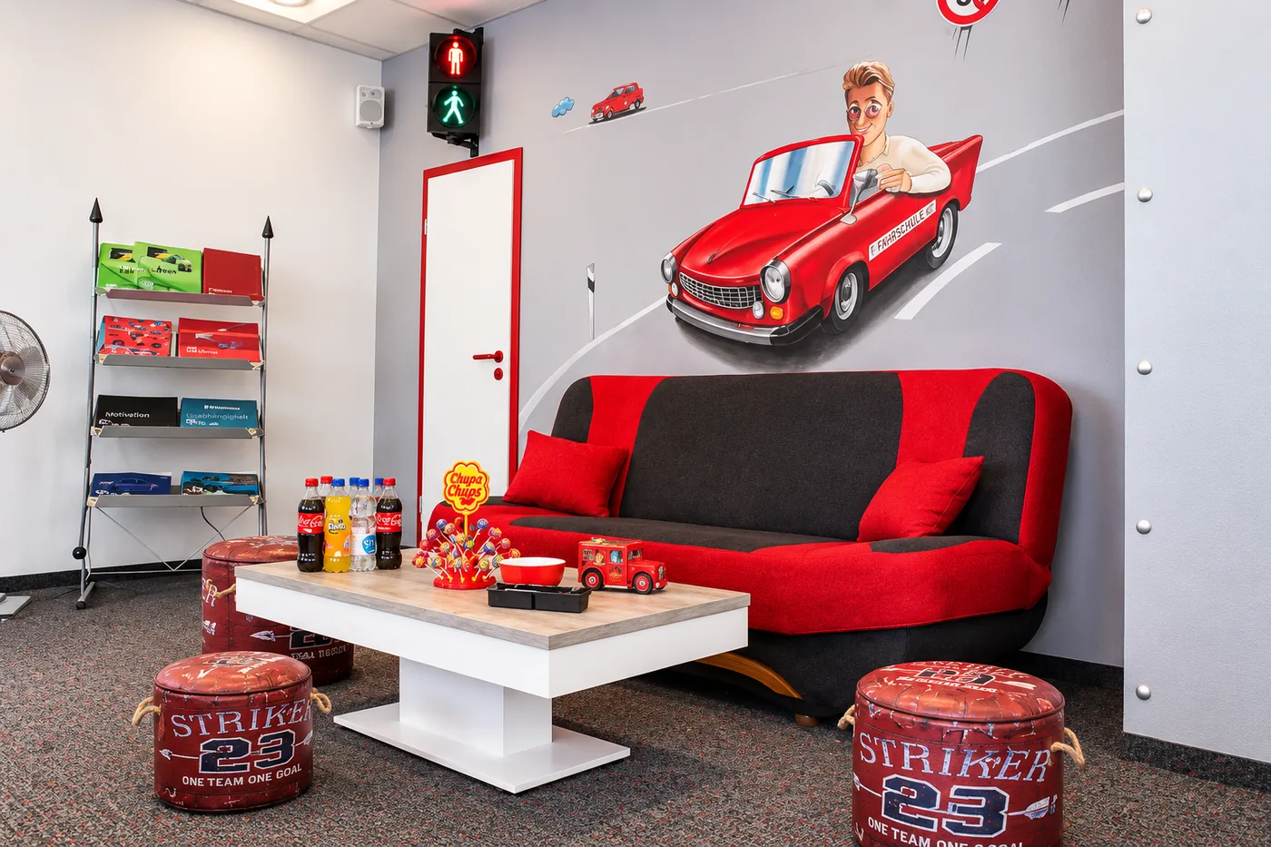 Der Wartebereich der Fahrschule mit rotem Sofa, Getränken und Zeitschriften
